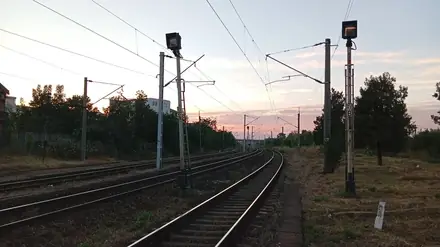 Signals and mast furniture at dusk, kilometre post in the grass to the right