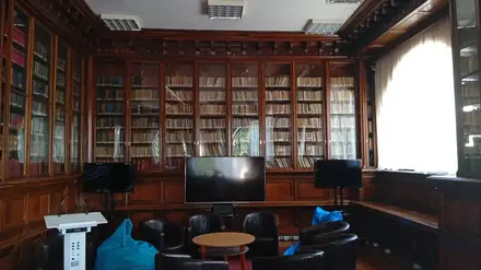 A reading room at the Aman County Library in Craiova — carved walnut bookcases floor to ceiling, screens and armchairs in front of them