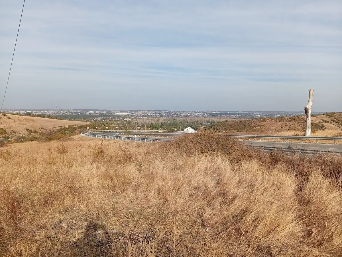 From the verge above the hairpins, 7 October 2026: the road below, Craiova across the horizon