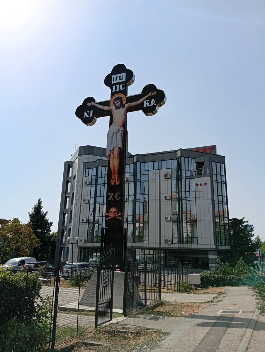 The roadside crucifix in its railed enclosure, Hotel Emma Est behind it