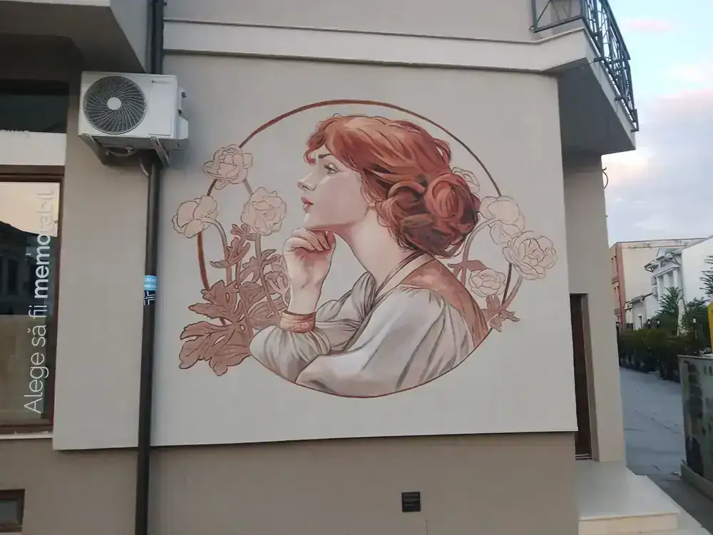 One of the painted walls on the side streets off the square — an Art Nouveau-style portrait in a ring of flowers