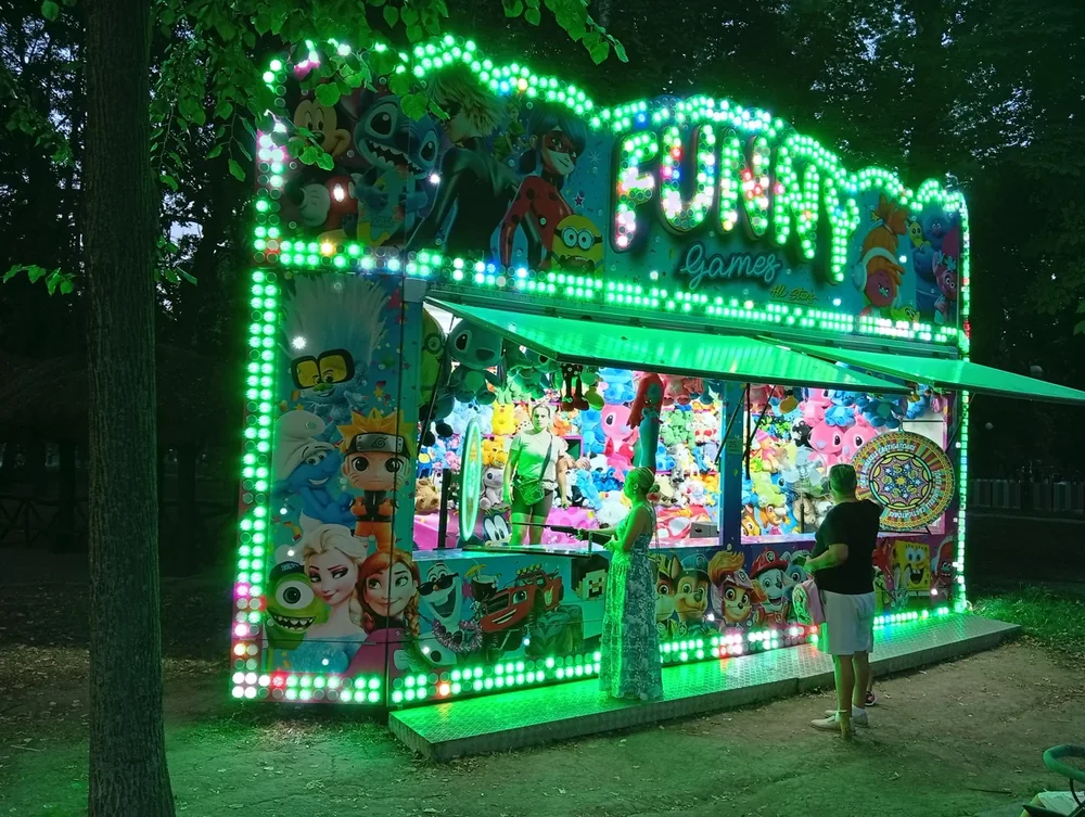 A prize stall at the fairground end, lit green from top to bottom