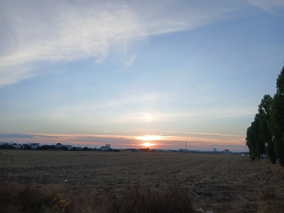 Sunset over a stubble field on the edge of the city, poplars on the right and the low skyline on the horizon, 8 October 2026