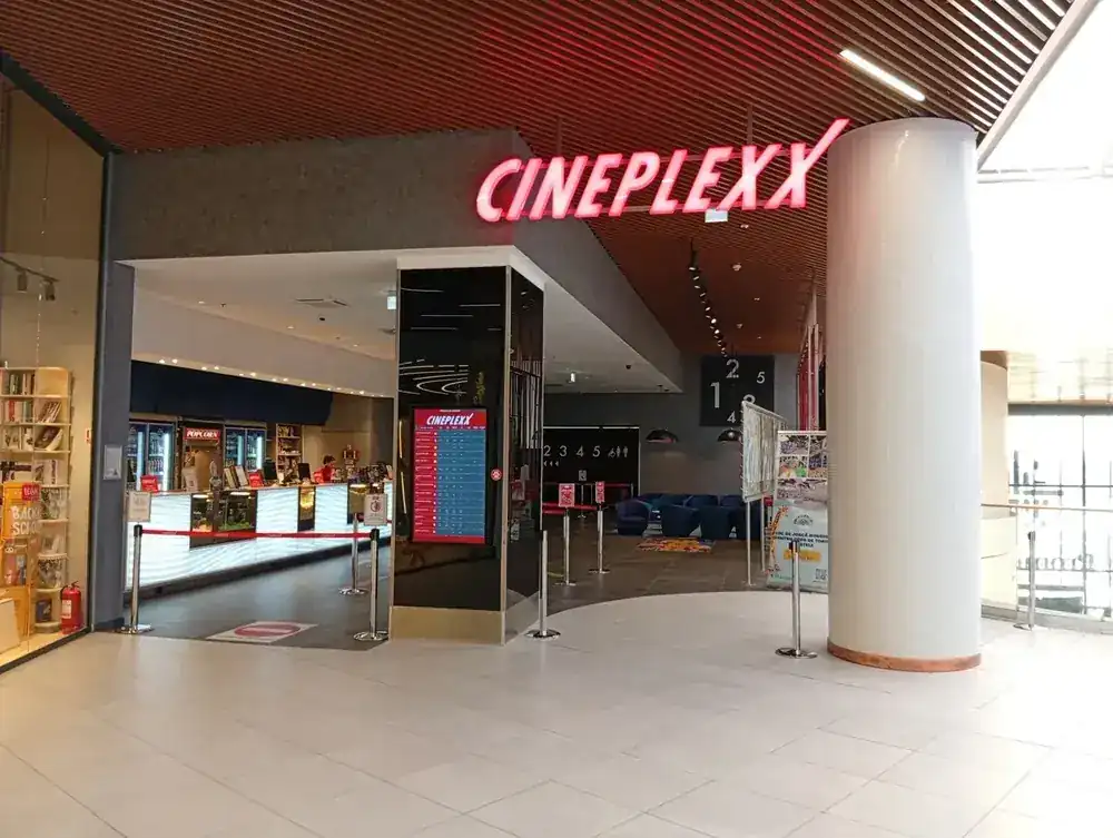 The Cineplexx entrance, ticket desk and screen board beside it