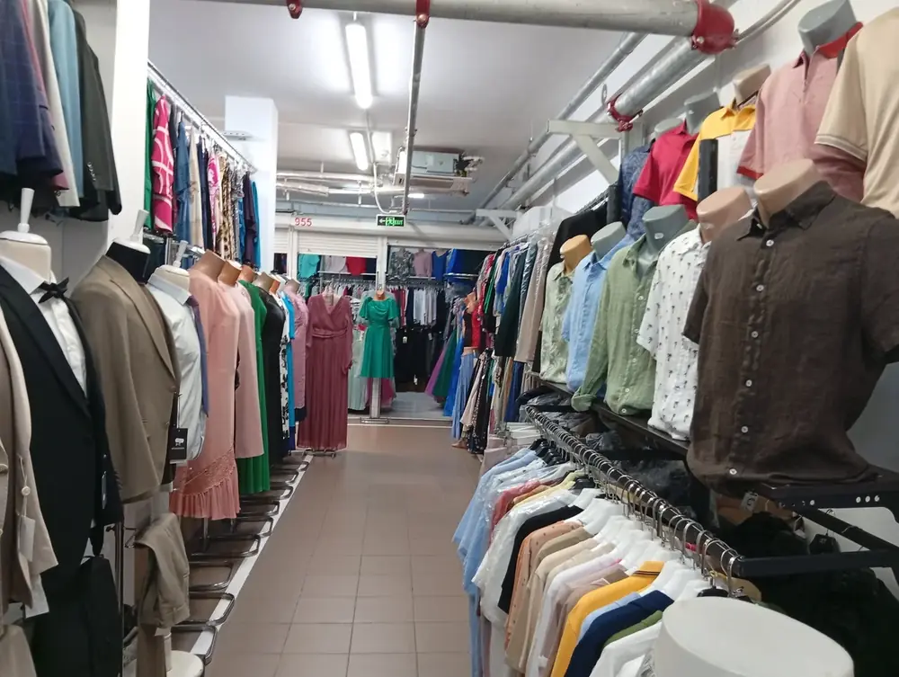 A narrow aisle — suits and shirts one side, dresses the other, stand numbers overhead