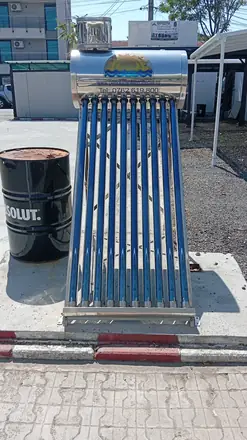 Evacuated-tube water heater on display by the kerb, tank on top, an Absolut drum for company