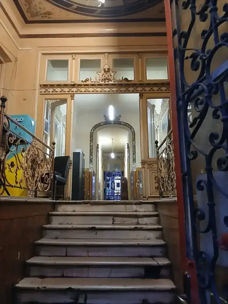 Just inside the street door of the old house the yard belongs to — painted ceiling, mirrors, wrought iron and a marble stair