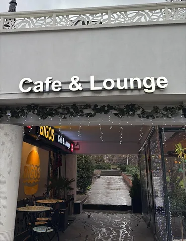The entrance to BIGOS Cafe & Lounge in Craiova under its Cafe & Lounge sign, with a path to the park behind