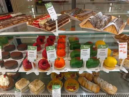 A bakery counter in Craiova — chocolate and pistachio-glazed croissants on wooden trays, with handwritten price tickets