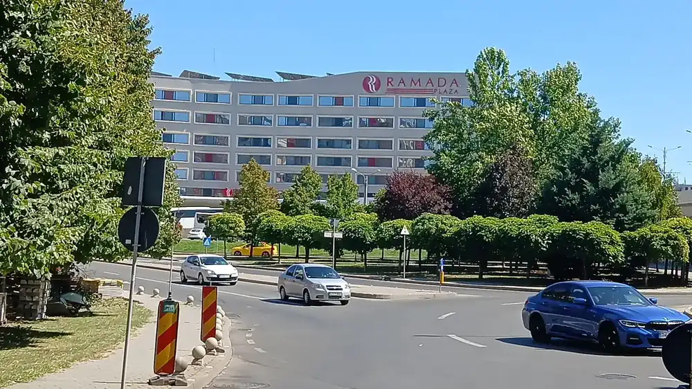 The hotel from the road on the far side of the junction — six floors, the name on the parapet, solar panels along the roofline