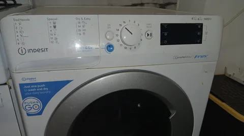 An Indesit washer-dryer control panel with the programme list, the round selector knob, the Start/Pause button and a dark display
